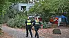 Zwei Polizeikräfte stehen auf einem gepflasterten Weg in einem begrünten Innenhof.