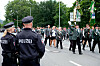 Polizisten sichern einen Schützenumzug mit Fahnen und zahlreichen Teilnehmern in Hannovers Innenstadt.