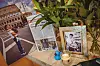 Erinnerungstisch im Bistro Lilly of the Valley mit gerahmtem Porträt, Zeitungsartikeln, Kerze und Pflanzen