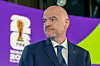 Gianni Infantino im dunklen Anzug vor FIFA-Branding und dem Logo der Weltmeisterschaft 2026