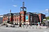 Kieler Hauptbahnhof mit rotem Backstein, Uhrturm, Fahrrädern und Passanten im Stadtzentrum