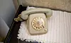 Beiges Telefon aus den 1950er-Jahren auf einer Spitzendecke im Flüchtlingssiedlungshaus des Kiekeberg-Museums.