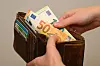 Frau zählt Euro-Geldscheine aus einem braunen Portemonnaie angesichts steigender Energiekosten.