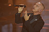 Eros Ramazzotti singt im schwarzen Anzug mit Mikrofon auf der beleuchteten Bühne in Sanremo.