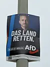 AfD-Wahlplakat mit Männerporträt und dem Slogan „Das Land retten.“ an einem Laternenmast