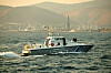 Boot der griechischen Küstenwache begleitet das Berlin Boat vor der bergigen Küste von Attika.
