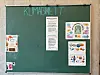 Grüne Tafel mit handschriftlicher Überschrift und mehreren Informationsplakaten
