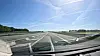Blick durch die Windschutzscheibe auf eine breite Fahrbahn mit Markierungen und grüner Landschaft.
