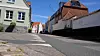 Ruhige Altstadtstraße mit historischen Häusern, Kopfsteinpflaster und ziegelgedeckten Dächern unter blauem Himmel.