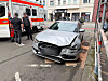 Beschädigte Mercedes-Limousine am Straßenrand neben einem Rettungsfahrzeug und mehreren Personen in der Stadt