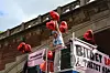 Politische Kundgebung mit roten Ballons und Transparenten vor einem historischen Gebäude