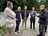 Fünf Männer sprechen auf einem gepflasterten Weg in einer begrünten Parkanlage.