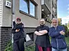 Drei Männer stehen mit verschränkten Armen vor einem Backsteingebäude mit der Hausnummer 28.
