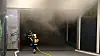 Feuerwehrleute gehen mit Atemschutz und Schlauch in ein stark verrauschtes Parkhaus.
