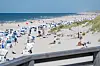Belebter Strand in Kampen auf Sylt mit Strandkörben, Dünen und Nordsee, gesehen über ein Geländer.