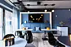 Modernes Caféinterieur mit blauen Wänden, Sitzgruppen, runden Tischen und großen Fenstern