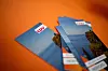 Mehrere blaue CDU-Werbeflyer liegen auf orangefarbenem Untergrund.