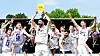 Janek Wrede hebt den LOTTO-Pokal hoch, umringt von jubelnden Spielern des HEBC.