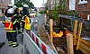 Feuerwehrleute bekämpfen Flammen in einer abgesperrten Baustelle an einer Straße.