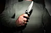 Mann hält in dunkler Umgebung ein Messer fest in der Hand; Symbolbild für Bedrohung und Gewalt.