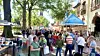 Besucher stöbern 2022 auf einem belebten Flohmarkt mit Verkaufsständen, Bäumen und historischen Gebäuden.