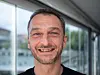 Jérôme Meunier, Chef im Restaurant Les Viviers, lächelt vor großen Fenstern in die Kamera.