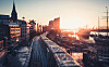 Stadtbahn fährt bei Sonnenuntergang durch ein dicht bebautes Stadtviertel.