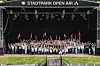 Große Gruppe mit roten Fahnen auf der Bühne des Stadtpark Open Air