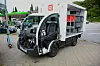 Beschädigter Kleintransporter steht neben einer Tankstelle, daneben ein E-Scooter und weitere Fahrzeuge.