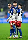 Miro Muheim, Daniel Elfadli und Fabio Vieira vom HSV stehen auf dem Rasen zusammen und halten sich während des Spiels.