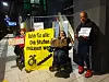 Drei Aktivisten protestieren mit Plakaten und Rollstühlen gegen Stufen an Bahnhöfen.