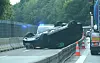 Umgekippter Pkw liegt auf dem Dach neben einer Autobahnbaustelle, gesichert durch Warnkegel und Fahrzeuge.