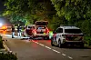 Polizeifahrzeuge und Einsatzkräfte sichern nachts eine Straße in Overasselt nach einer Schießerei.