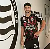 Fußballspieler im schwarz-roten LASK-Trikot posiert in einem Vereinsgang.