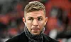 TV-Experte Christoph Kramer mit Schal vor unscharfer Stadionkulisse in Leverkusen.