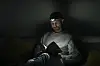 Florian Neubauer liest in seiner Wohnung mit einer Kopflampe ein Buch auf dem Sofa.
