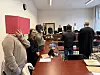 Blick in den Gerichtssaal. Alle Prozessbeteiligten stehen. Die Angeklagten halten sich etwas vor ihre Gesichter.