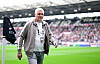 Andreas Bornemann geht im Millerntor-Stadion am Spielfeldrand vor Fans und FC-St.-Pauli-Flagge entlang.