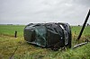 Beschädigtes Auto liegt nach einem Unfall auf der Seite in einem Feld.