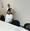 Zwei Männer in einem Büro, einer sitzt am Tisch, der andere steht hinter ihm.