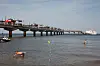 Seebrücke in Miedzyzdroje ragt über die Ostsee; Badegäste schwimmen im Vordergrund, ein Schiff liegt rechts.