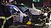 Feuerwehrleute sichern ein stark beschädigtes Taxi nach einem Unfall auf regennasser Straße in Hamburg.