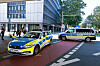 Blau-gelbes Polizeiauto und Polizeibus stehen an einer belebten innerstädtischen Kreuzung.