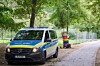 Blau-silberner Mercedes-Polizeiwagen auf einem Waldweg mit Absperrgittern im Hintergrund