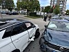 Zwei beschädigte Autos stehen nach einer Kollision auf einer Straße, mehrere Menschen sind im Hintergrund zu sehen.