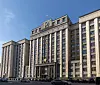 Fassade der Staatsduma in Moskau mit russischer Flagge und Autos vor dem Parlamentsgebäude