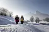 Zwei Wandernde auf einem verschneiten Weg vor schneebedeckten Bergen