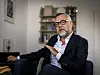 Michael Roth sitzt im dunklen Sakko in seiner Berliner Wohnung und gestikuliert während eines Interviews.