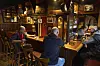 Gäste sitzen in der rustikalen Gaststätte Drei Eichen in Hamburg-Groß Borstel an Theke und Tischen.