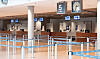 Leere Flughafenhalle mit Check-in-Schaltern, Absperrbändern, Uhr und Anzeigetafeln